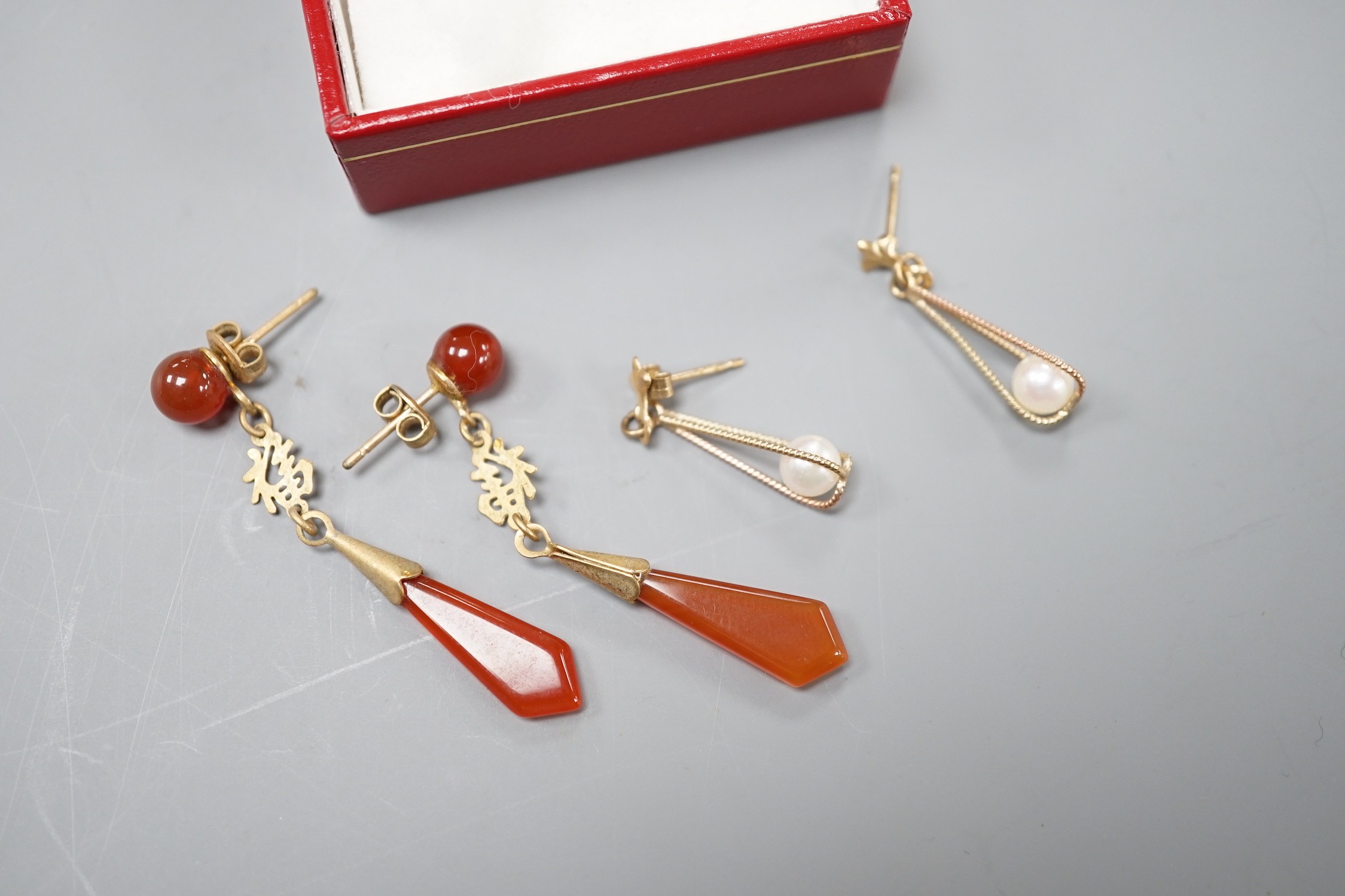 A modern pair of 585 yellow metal and cultured pearl ear studs, a pair of yellow metal and carnelian set drop earrings and a similar pair of cultured pearl earrings.